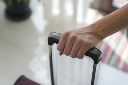 Close up shot of woman hand holding suitcase handle.Cropped image with blurred background.の写真素材