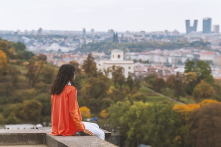 View from back. Woman enjoying the view of the city on an autumn dayの写真素材