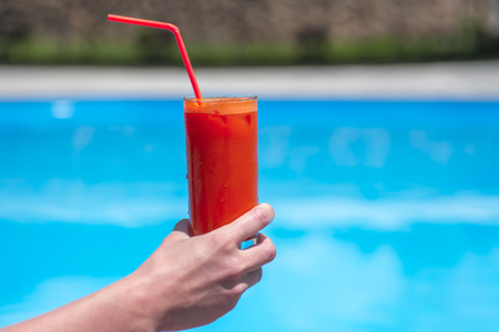 juice in a glass on the wooden table by the pool.の写真素材