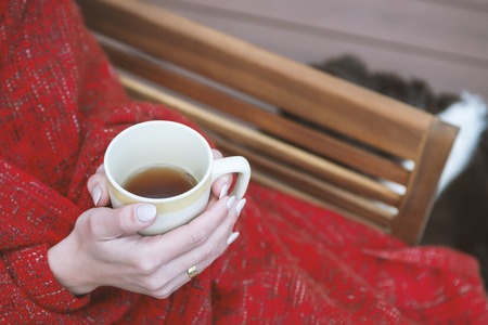 Female holding cup of hot drink in cozy atmosphereの写真素材