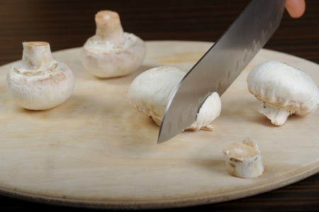 white fresh mushrooms being cut on the tableの写真素材