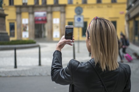 Woman tourist taking picture with mobile camera in the streetの写真素材