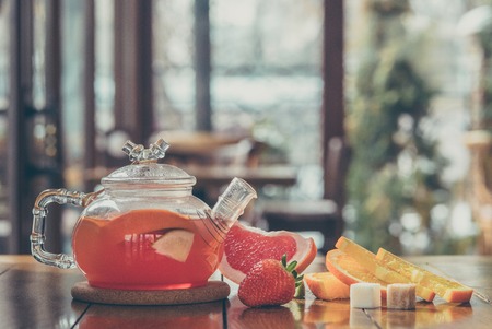 Fruit red tea in a glass kettle and cup on the wooden backgroundの写真素材