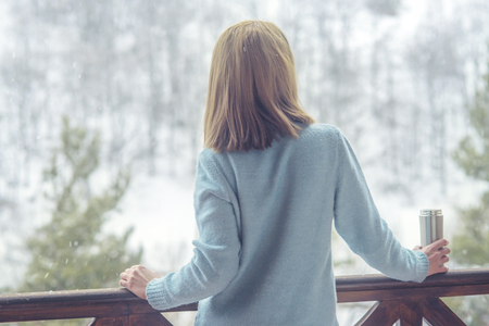 Woman in the  of a winter forest with bottle in handsの写真素材