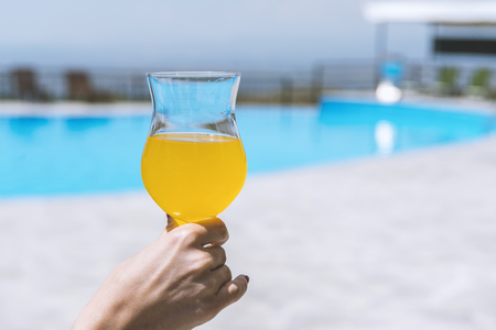 glass of fresh orange or pineapple juice by the poolsideの写真素材