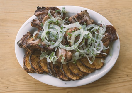 pork shish kebabs and potatoes in a white plate on a wooden tableの写真素材