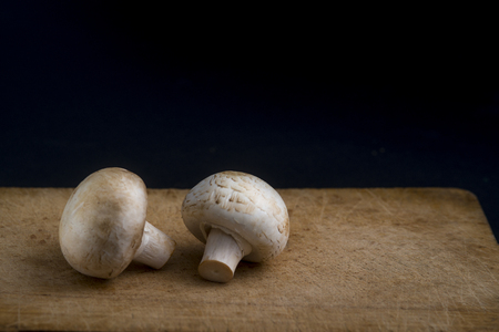 champignon mushrooms on a wooden board on a black backgroundの写真素材