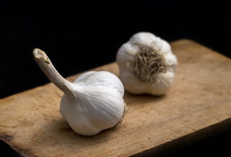 garlic on wooden board on black backgroundの写真素材