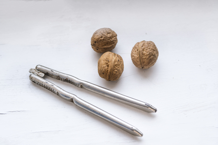 Two walnuts and vintage nutcracker on a white background