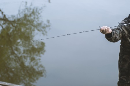 Man fishing with fishing rod on pond in spring day. Hobbies, recreation and leisure outdoor activities concept.の写真素材