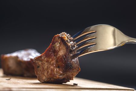 Piece of meat on a fork, darkの写真素材