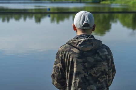 Fisherman with rod, spinning reel on the river bank. Fishing on nature. The concept of a rural...