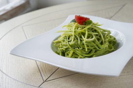 Green spinach spaghetti with cheese and tomato on wooden tableの写真素材