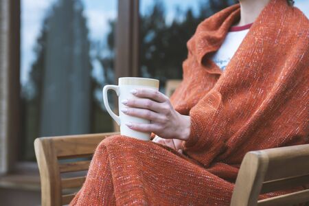 Female holding cup of hot drink in cozy atmosphere