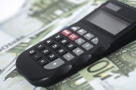 A few euros and a calculator on the table, finance and savings. Business conceptの写真素材