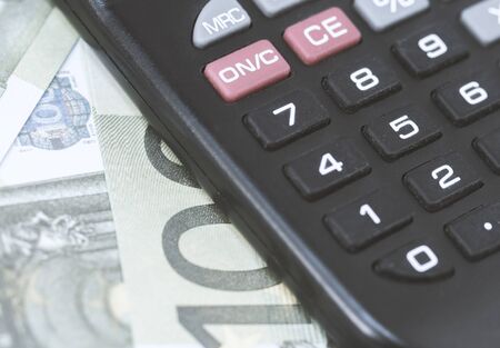 A few euros and a calculator on the table, finance and savings. Business conceptの写真素材
