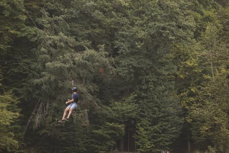 Tourist ride on the Zipline through the canyon. Tourist in  helmets is riding on a cable carの写真素材
