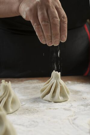 Chef cook making khinkali  on wooden table. Process preparation georgian meal. food concept.の写真素材