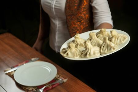 Waiter brings a plate of khinkali.Georgian cuisine.khinkali with on white plateの写真素材