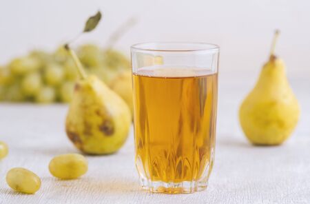 Juice of pears and grapes in a glass on a white wooden backgroundの写真素材