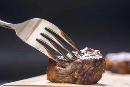 Piece of meat on a fork, darkの写真素材