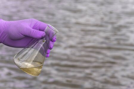 Sample water from the river for analysis. Hand in glove holding a test tube.ecology conceptの写真素材