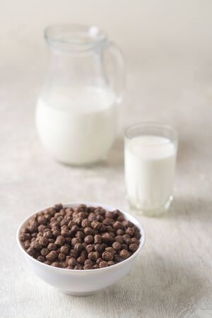 Bowl with chocolate corn balls and milk, on white woodenの写真素材