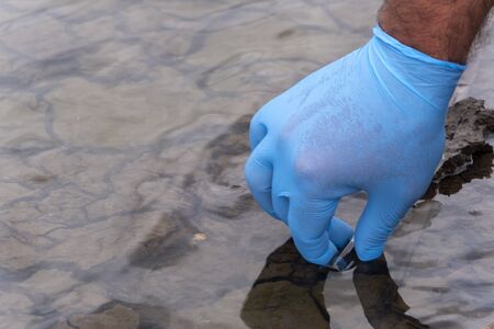 Sample water from the river for analysis. Hand in glove holding a test tube.ecology concept