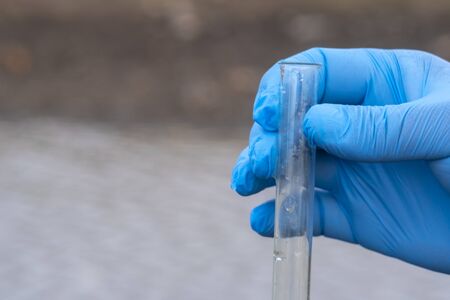 Sample water from the river for analysis. Hand in glove holding a test tube.ecology conceptの写真素材