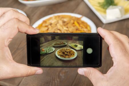 Smartphone photo of food.Mans hands make phone photography of l traditional meals. lunch or...