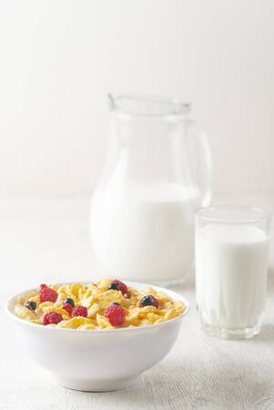 Healthy breakfast with cereal and blueberry and raspberry.Bowl with healthy cornflakes, milk and berries on white table.Tasty circle cornflakes.oatmeal with fruits. Diet concept.の写真素材