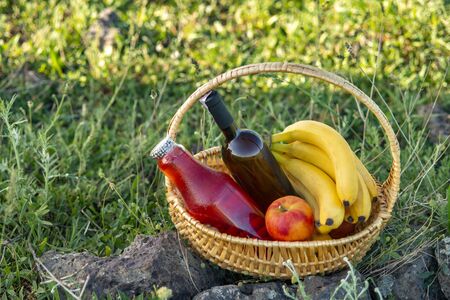 Picnic basket with wine and fruit on green lawn .の写真素材
