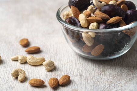 Mix of dates and nuts in plate on a white wood background .healthy foodの写真素材