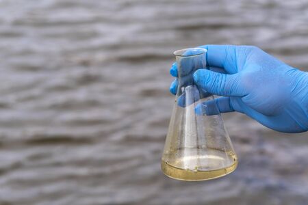 A water sample from the river. Hand in glove collects water in a test tube. ecology conceptの写真素材