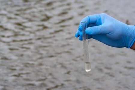 A water sample from the river. Hand in glove collects water in a test tube. ecology conceptの写真素材
