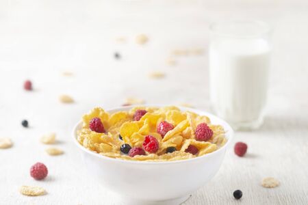 Healthy breakfast with cereal and blueberry and raspberry.Bowl with healthy cornflakes, milk and...