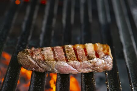 grilling steaks on flaming grill and shot with selective focus