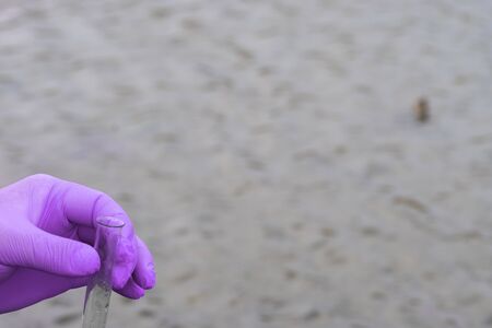 A water sample from the river. Hand in glove collects water in a test tube. ecology concept