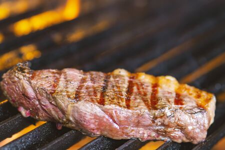 grilling steaks on flaming grill and shot with selective focus