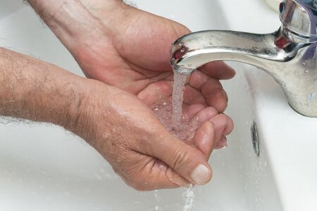 Old man washes his hands in the bathroom.の写真素材