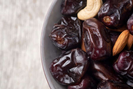 Mix of dates and nuts in plate on a white wood background .Top view.healthy food