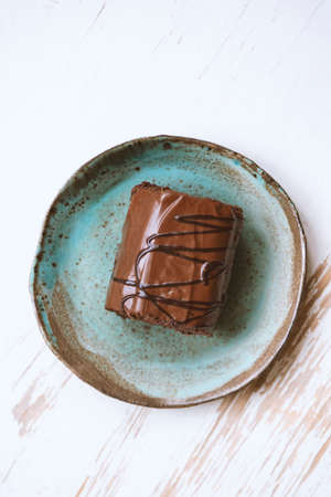 Chocolate roll cake in plate on white wooden background.