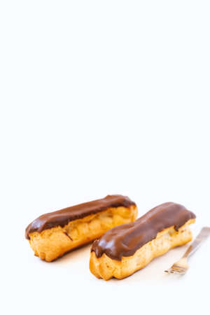 Two eclairs with custard and chocolate icing on a white background
