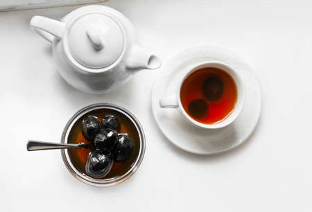 Teapot, cup with tea and jam jar of walnuts on a white background. Top viewの写真素材