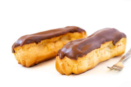 Two eclairs with custard and chocolate icing on a white background