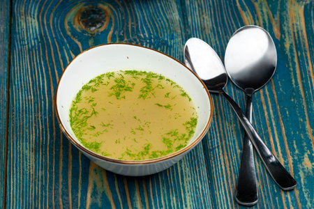 chicken broth in white bowl on blue deskの写真素材