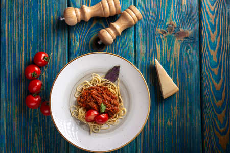 Pasta with meat, tomato sauce and vegetables in blue wooden desk. top viewの写真素材