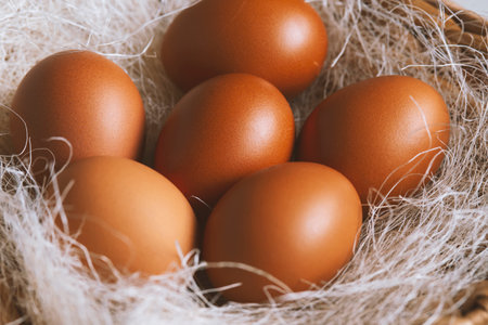 Brown chicken eggs in a wicker basket with straw