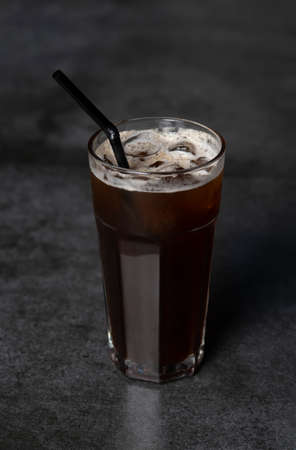 Ice coffee in a tall glass over a. Cold summer drink on a dark background with copy spaceの写真素材