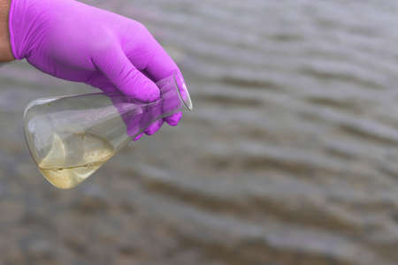 A water sample from the river. Hand in glove collects water in a test tube. ecology conceptの写真素材